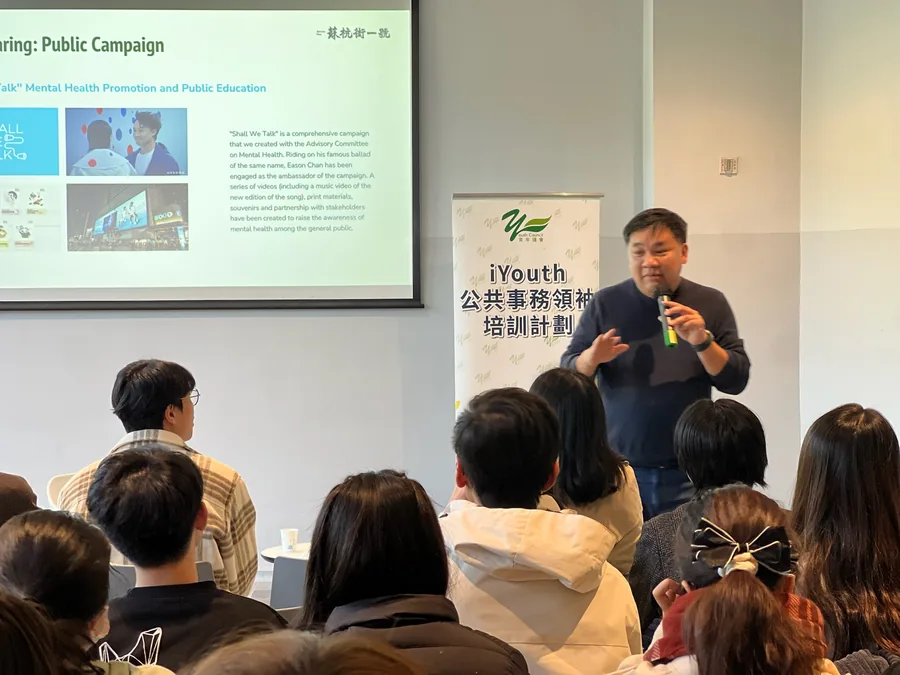 羅永聰先生站在投影幕前向席上學員分享，幕上顯示「陪我講」精神健康推廣計劃的簡報。