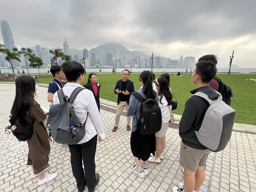 iYouth 學員在戶外參觀期間步行，背景為海景。