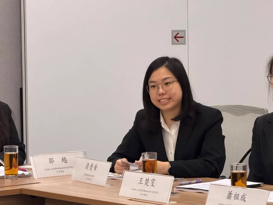 一位戴眼鏡的女學員在會議桌前發言，桌面擺放印有學員姓名的座位名牌。